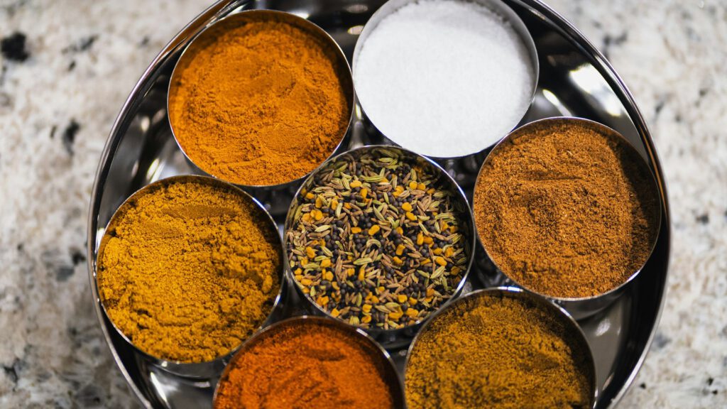 Runde Gewürzdose mit mehreren Metallschalen voller bunter Gewürze