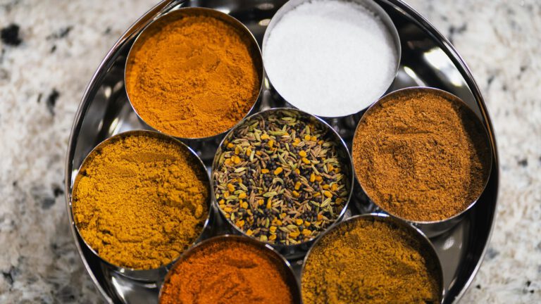 Runde Gewürzdose mit mehreren Metallschalen voller bunter Gewürze