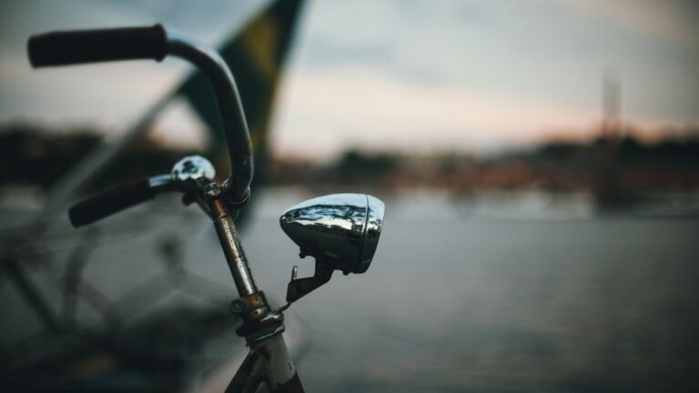Fahrradlenker mit Frontscheinwerfer in der Abenddämmerung am Wasser
