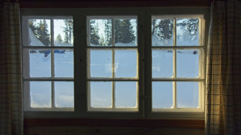 Altes Sprossenfenster mit Holzrahmen, draußen liegt Schnee